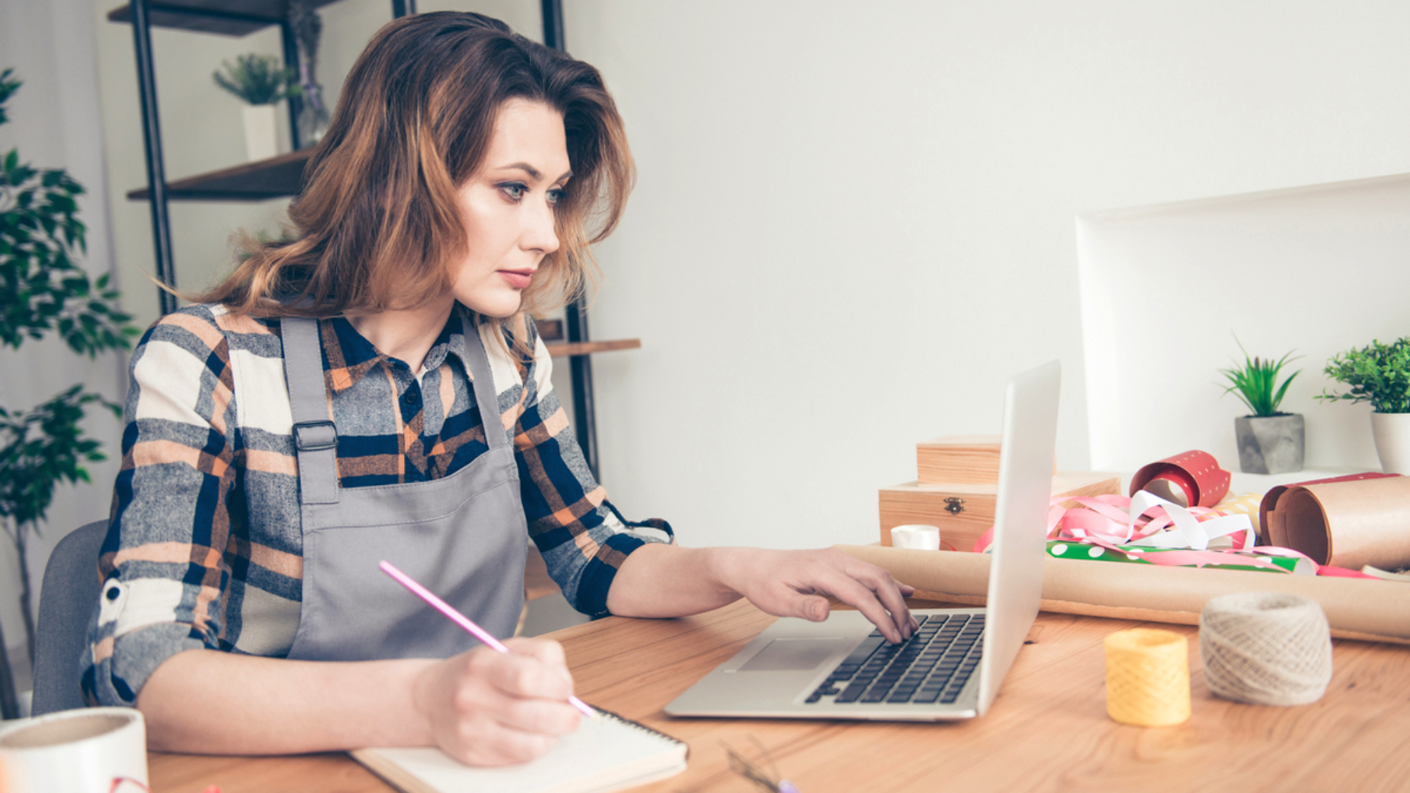 Portrait serious focused lady vendor use modern technology pc make orders bouquets bunches plan holiday 8-mrach consumerism floral natural nature wavy curly haircut trendy stylish outfit plaid indoors.
